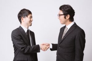 男性２人が握手する姿